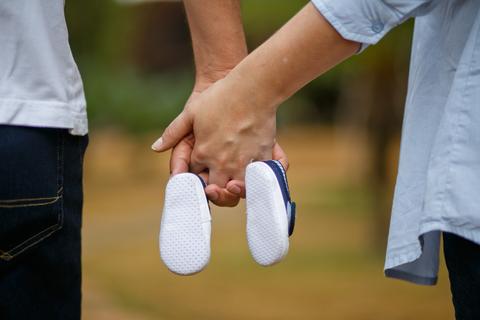 Parents qui se tiennent la main en tenant des chaussures de bébé